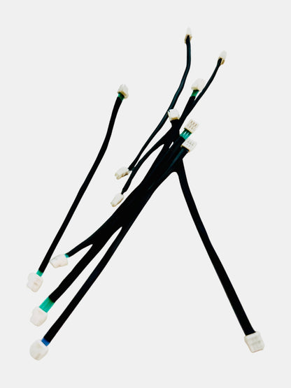 Several black cables with white connectors, some marked with colored tape, on a plain white background.