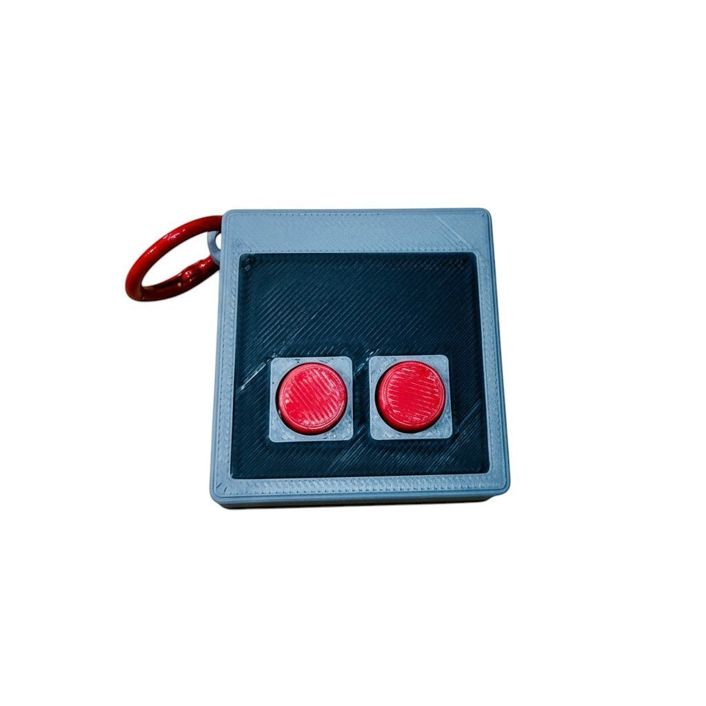 Wacky McLovin Prints NES-inspired controller keychain, grey with black textured panel and two red buttons. 3D printed.